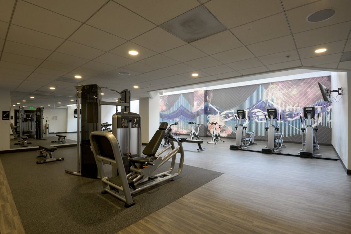 Spacious modern gym with exercise equipment and vibrant wall art for a dynamic workout environment.