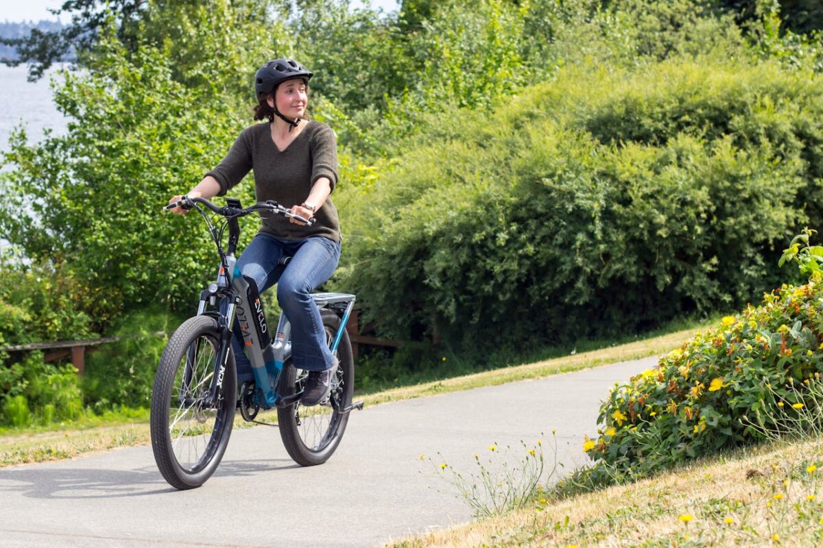 Woman biking on a scenic path in Seattle, showcasing modern electric bike and lifestyle.