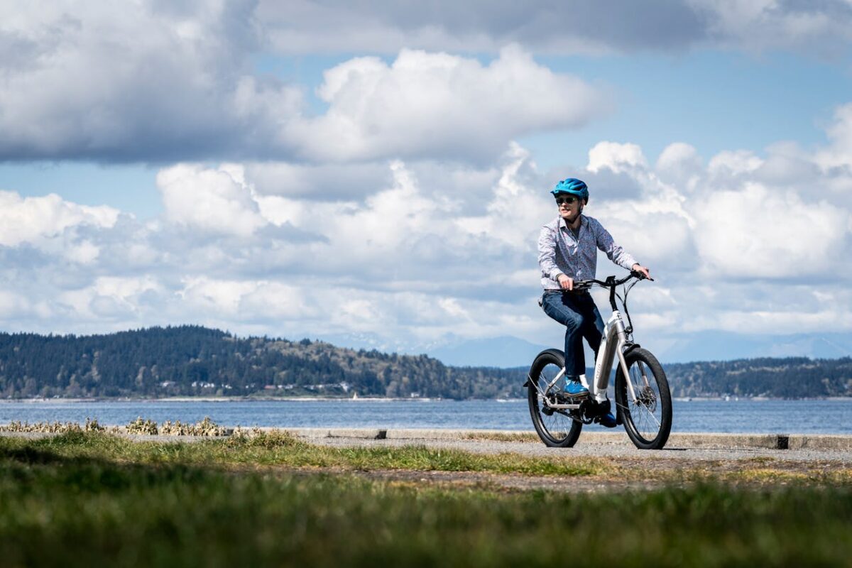 Person riding an electric bike along the Seattle waterfront on a sunny day with scenic views.