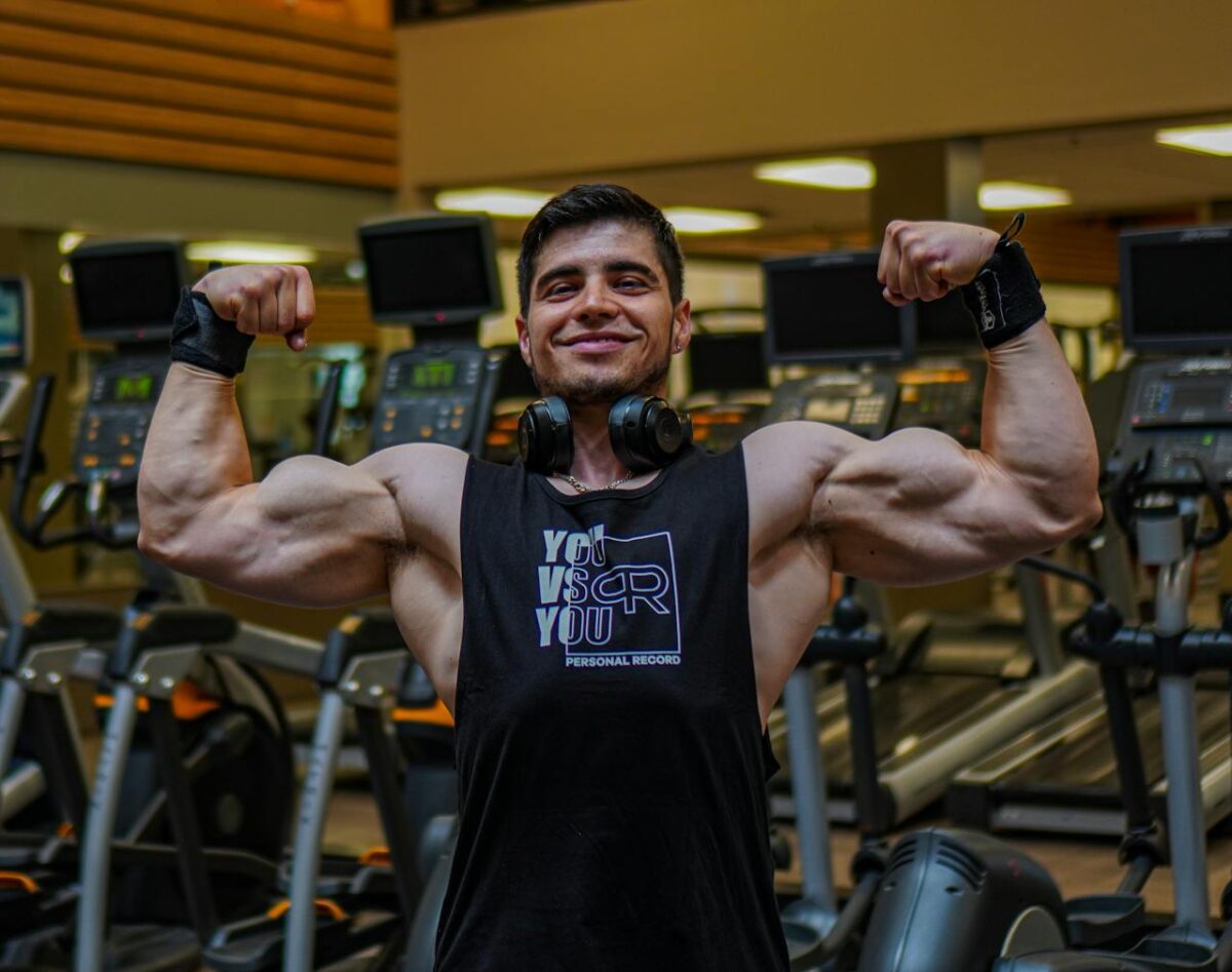 Portrait of a smiling bodybuilder flexing muscles in a modern gym.