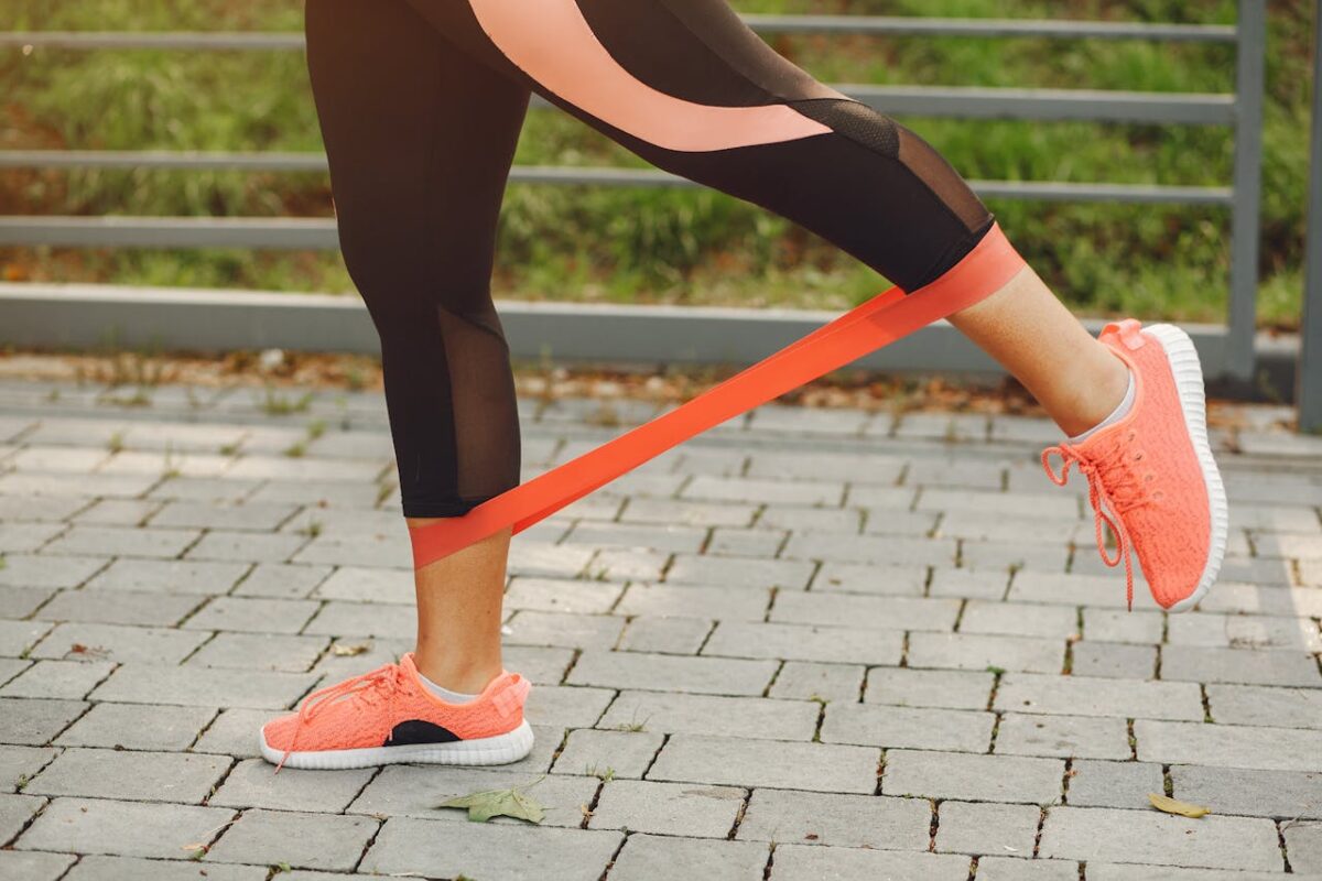Close-up of a woman exercising with a resistance band in a park.