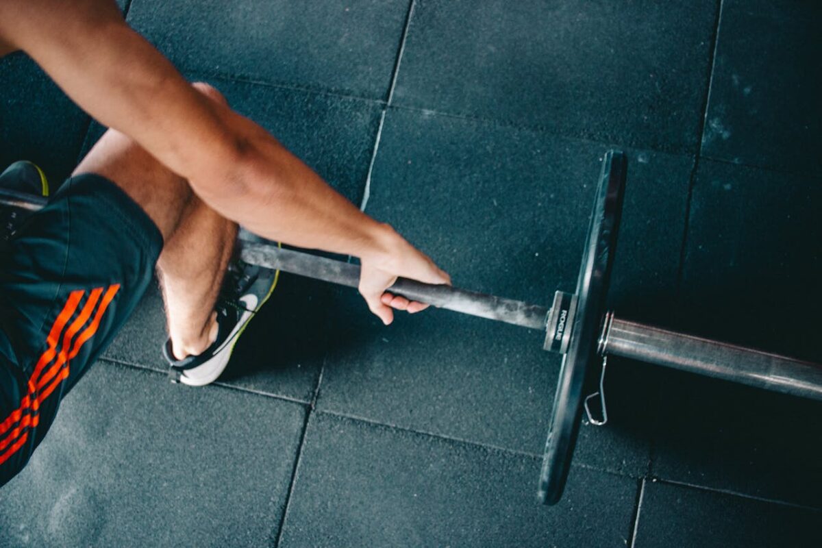 about-bg Close-up of an athletic man lifting a barbell in a gym setting, focusing on strength and fitness.